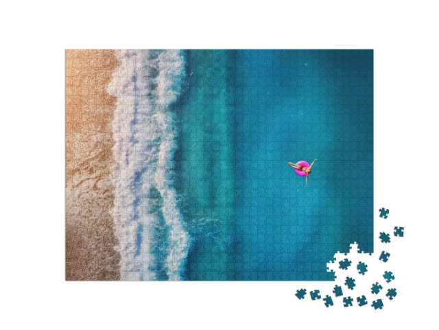 Puzzle 1000 Teile „Luftaufnahme einer jungen Frau auf einem rosa Schwimmring im Meer in Oludeniz“
